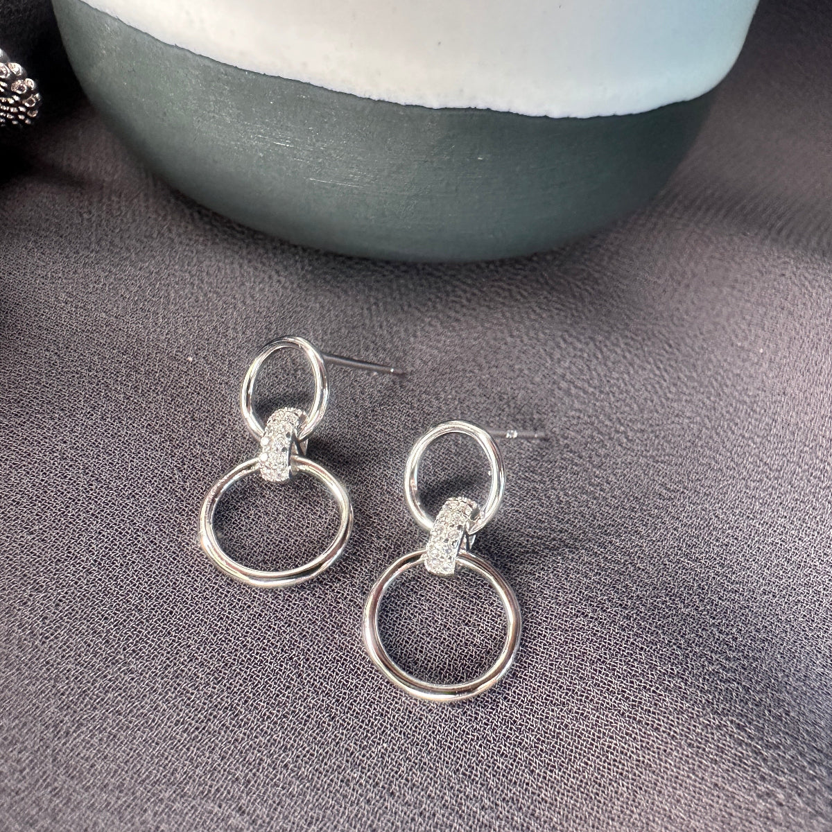 Silver earrings with two interlocking rings on a gray surface