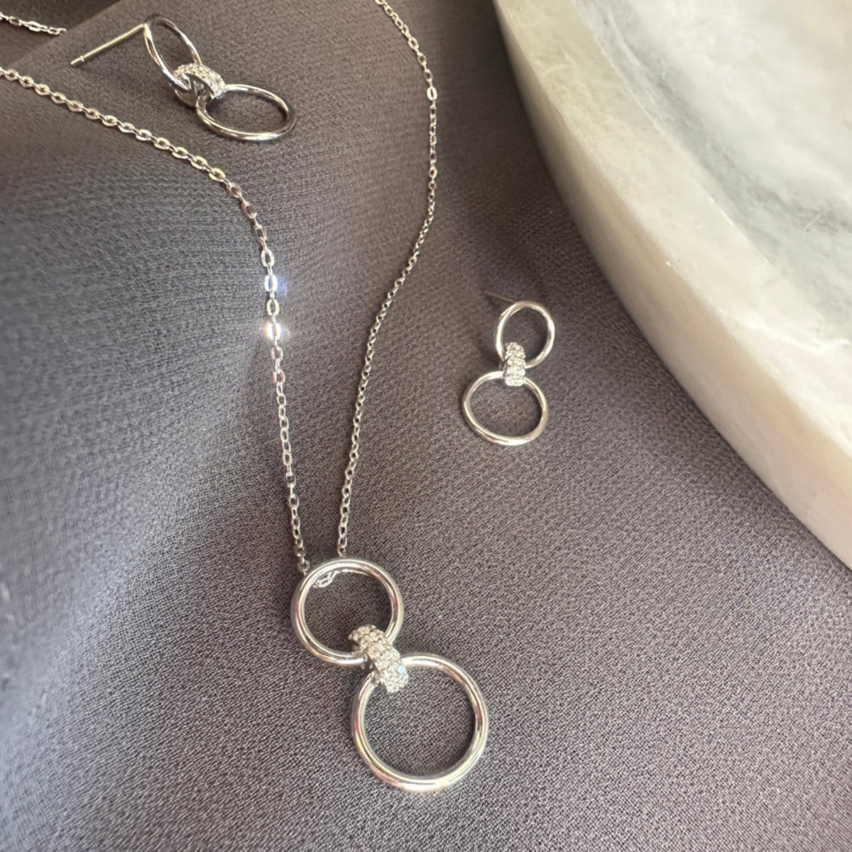 Sparkly Silver necklace and earrings on a grey surface