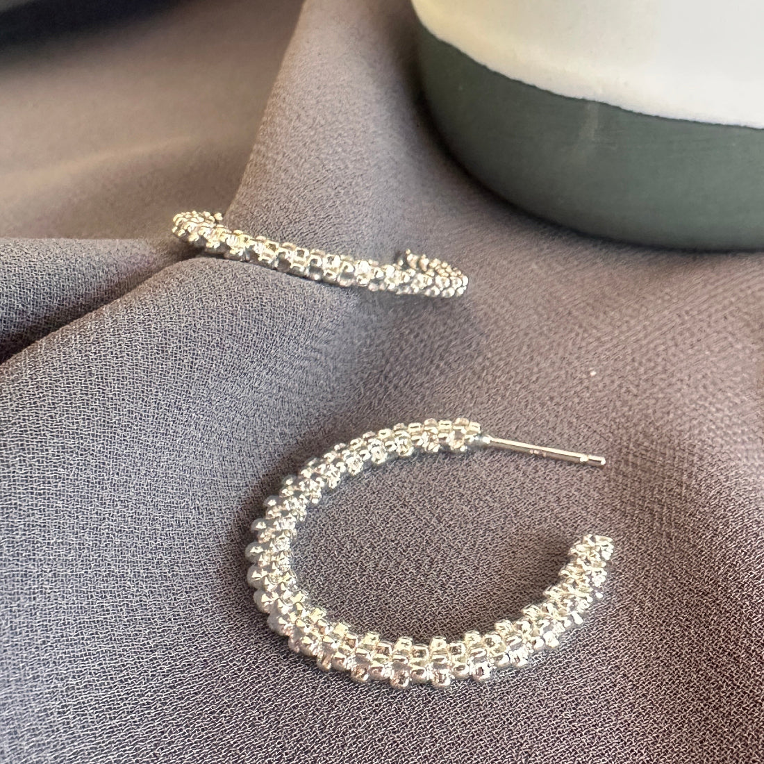 Silver hoop earrings on a textured gray surface