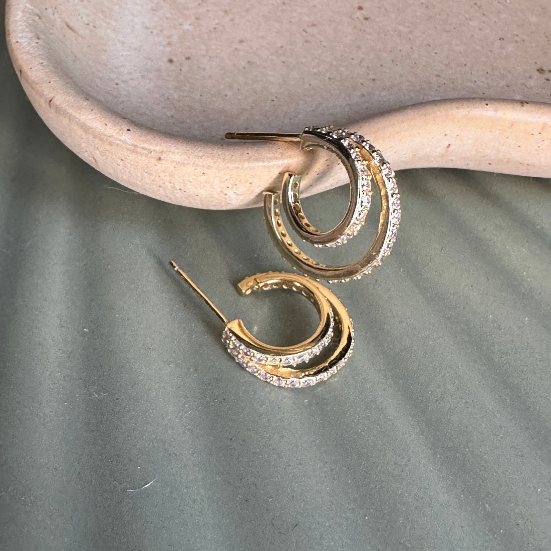Gold hoop earrings with diamond accents on a stone surface