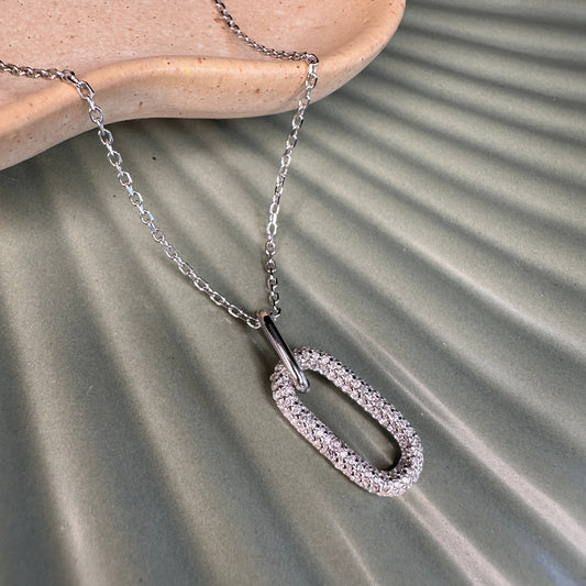 Silver pendant necklace laid on ceramic ground