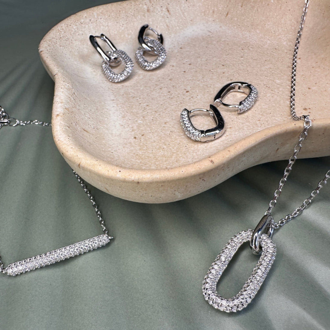 Collection of silver jewellery with crystal pave setting on ceramic background