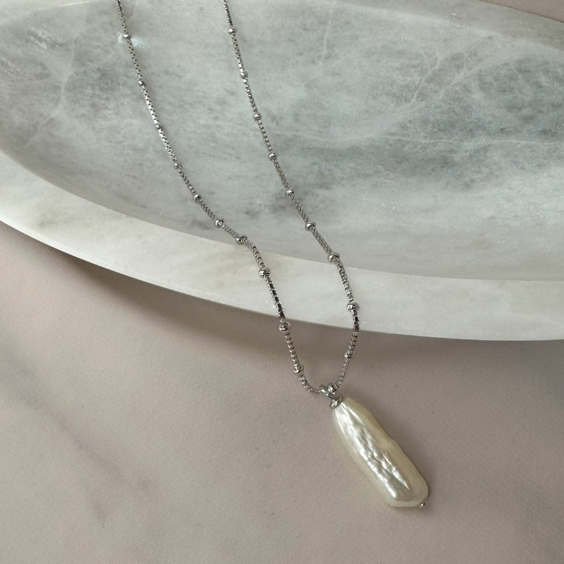 a unique peandant with baroque pearl laid on marble tray