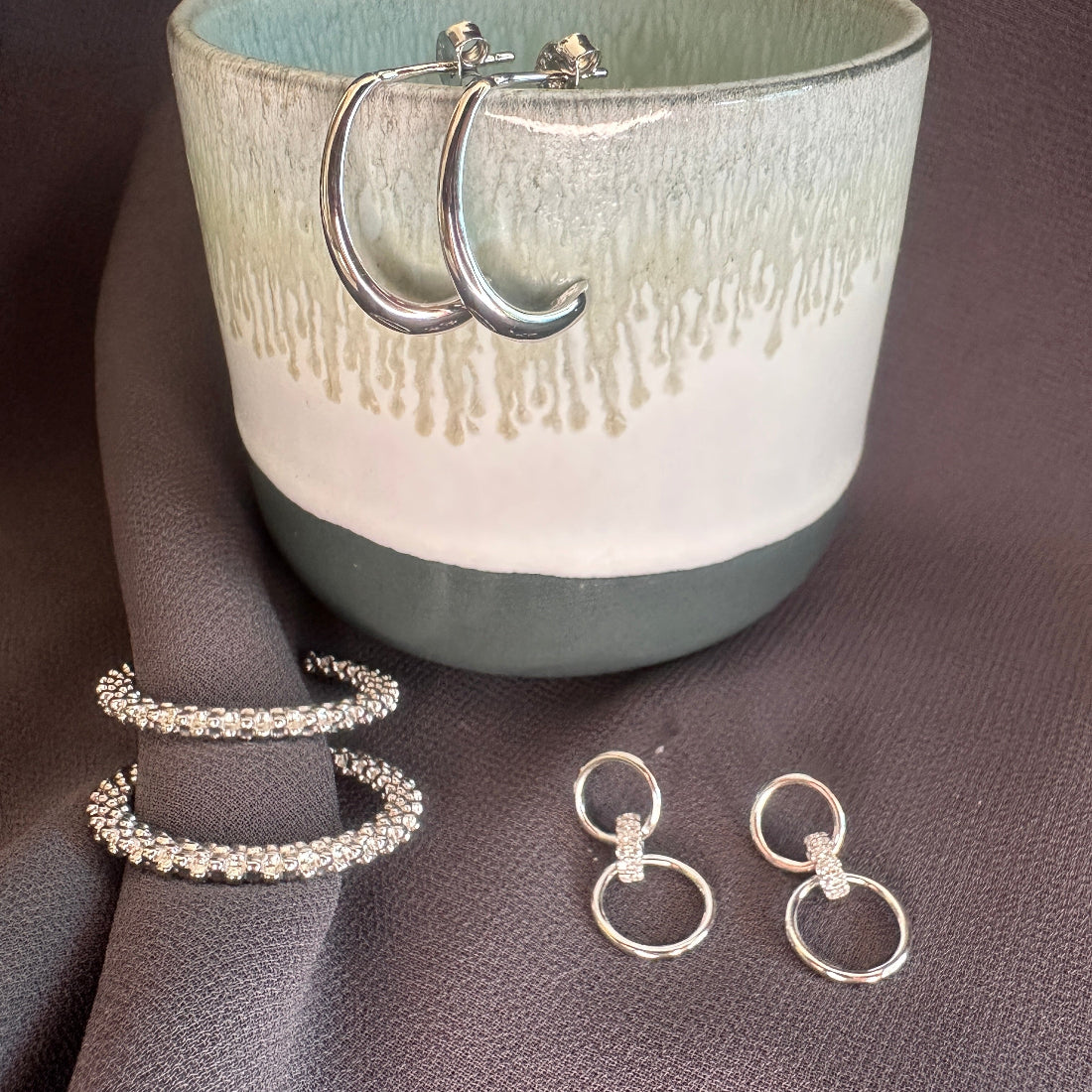 collection of jewllery on pink ground and ceramic jar