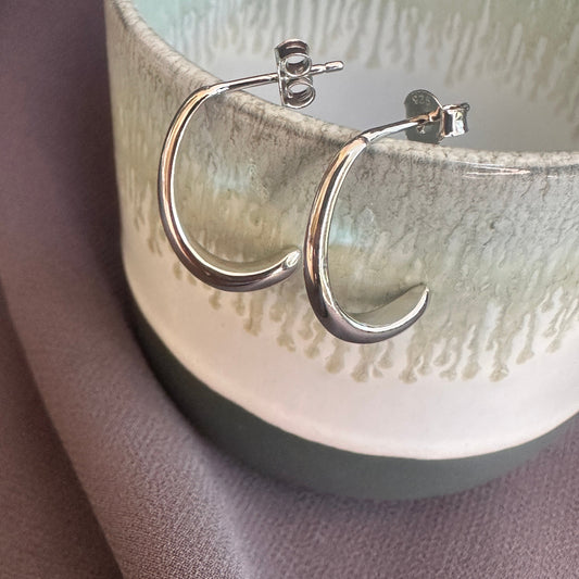 Silver hoop earrings on a textured ceramic surface