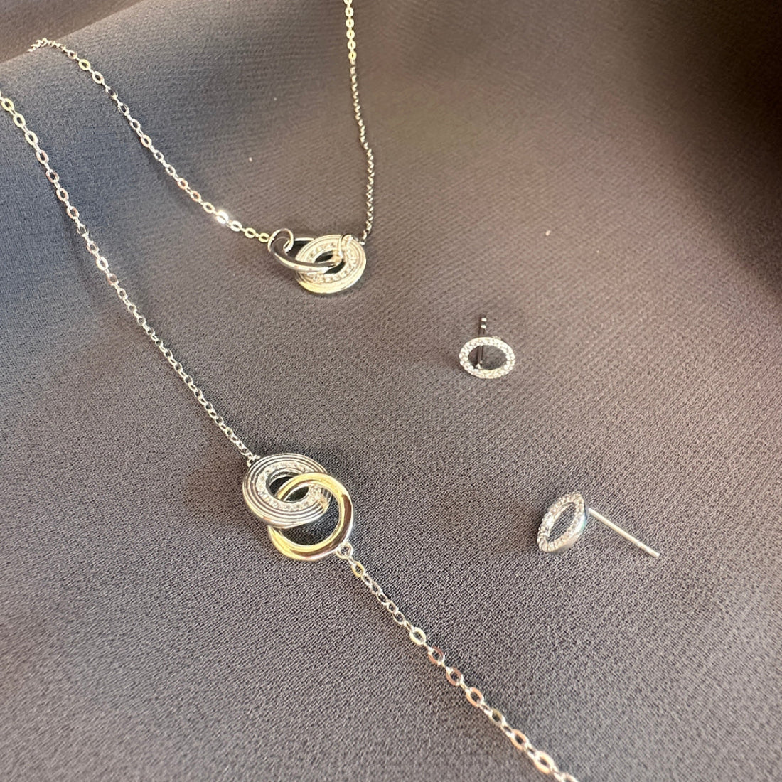 Unique silver necklace and earrings on a grey surface