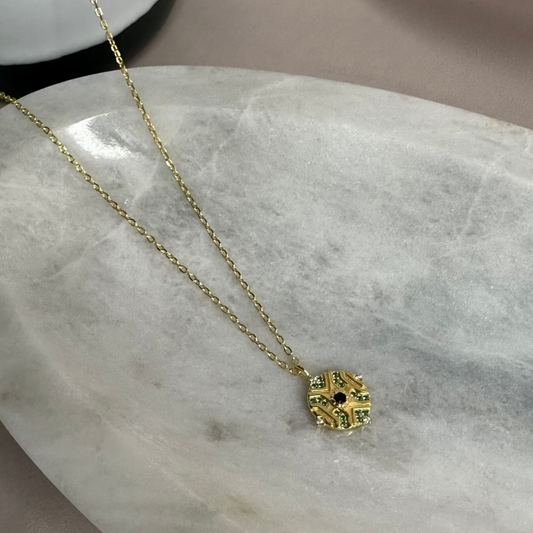 A silver pendant necklace with a geometric pattern inspired by morocco, displayed on a marble surface.