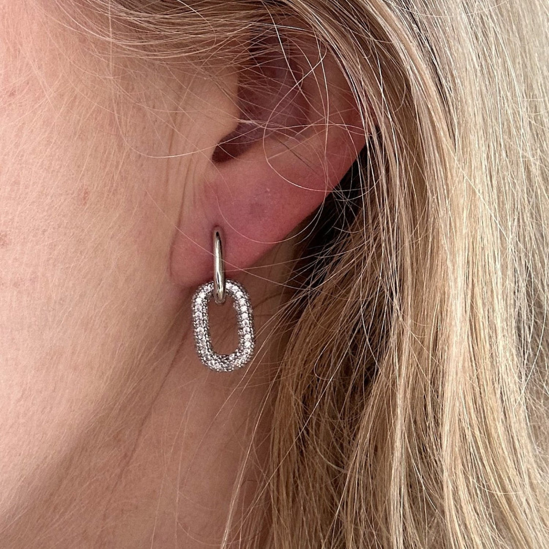 oval hoop earring with pave encrusted oval charm on a models ear