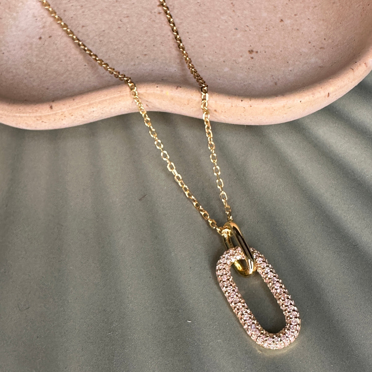 Gold necklace with a unique pendant on a textured surface