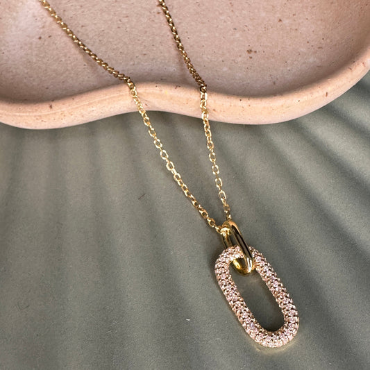 Gold necklace with a unique pendant on a textured surface