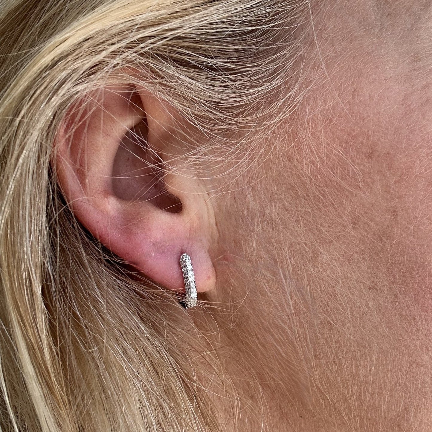 Silver oval-shaped gemstone earrings with a pave gemstone charm worn on a model.