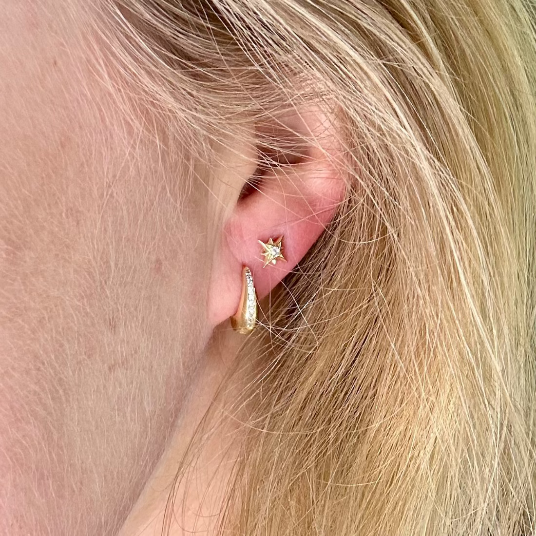 model wearing a star stud earring and a cubic ziconia huggie earring in gold