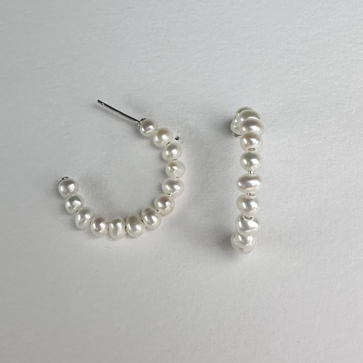 silver pearl hoop earings on a white matte plate