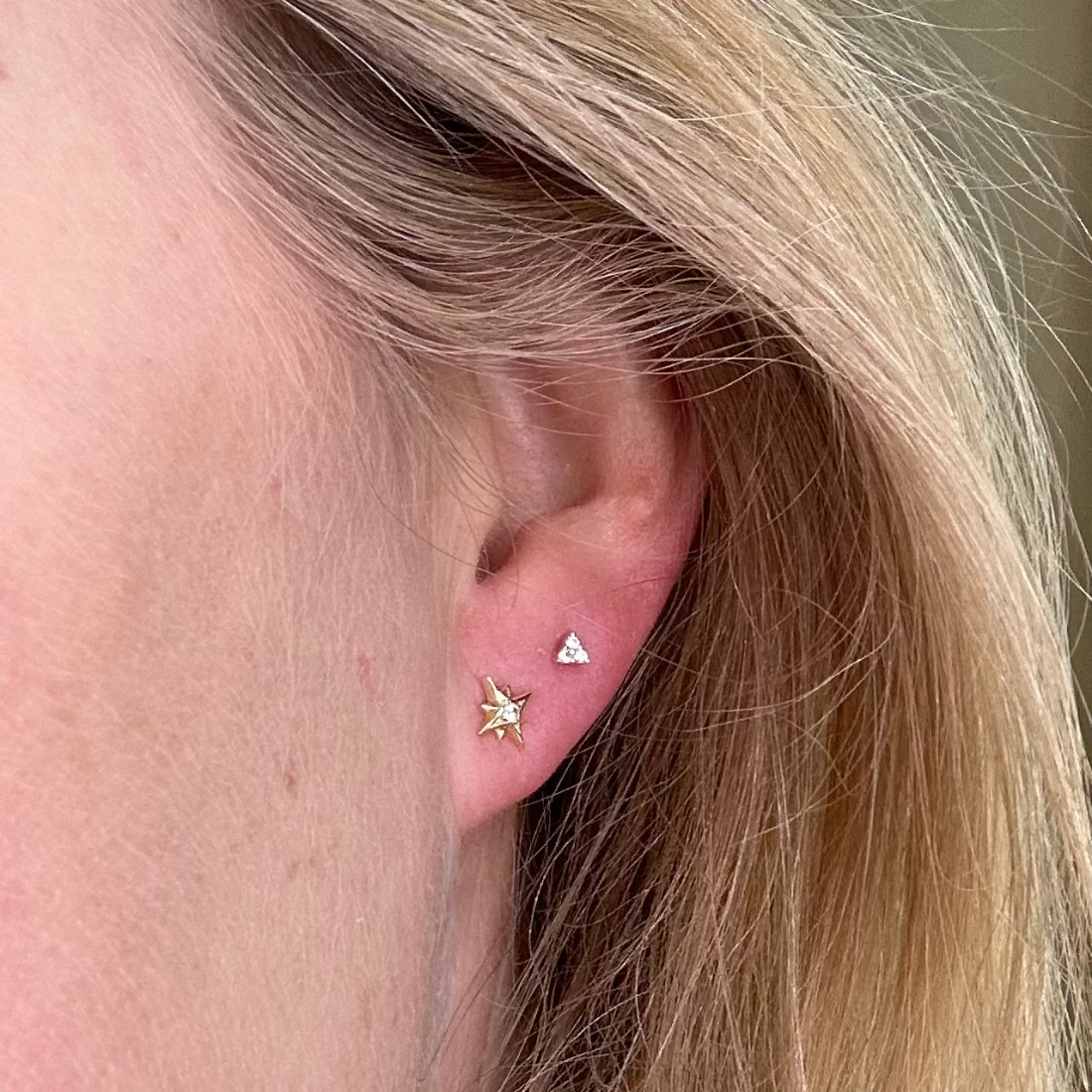 model wearing 2 studs, a star stud with gemstone and a triangle stud with 3 shining cubic ziconias.