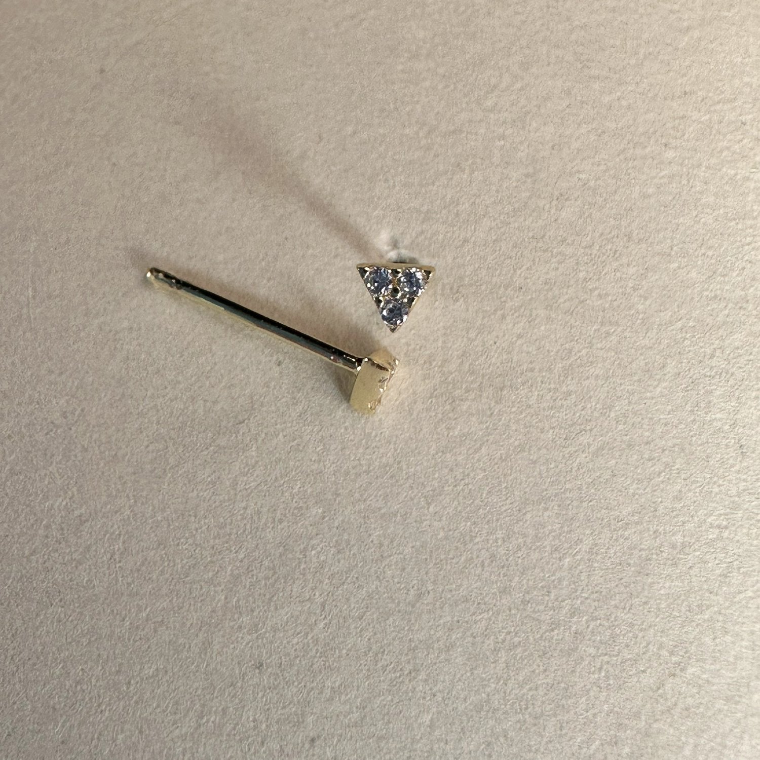 A pair of triangular gemstone stud earrings with a sparkling white faceted surface, displayed against a white background.