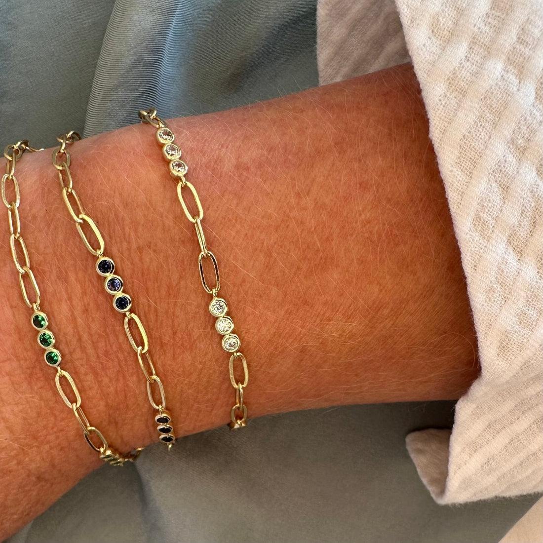 A series of round, multicolored gemstone bracelets with a gold-chain.