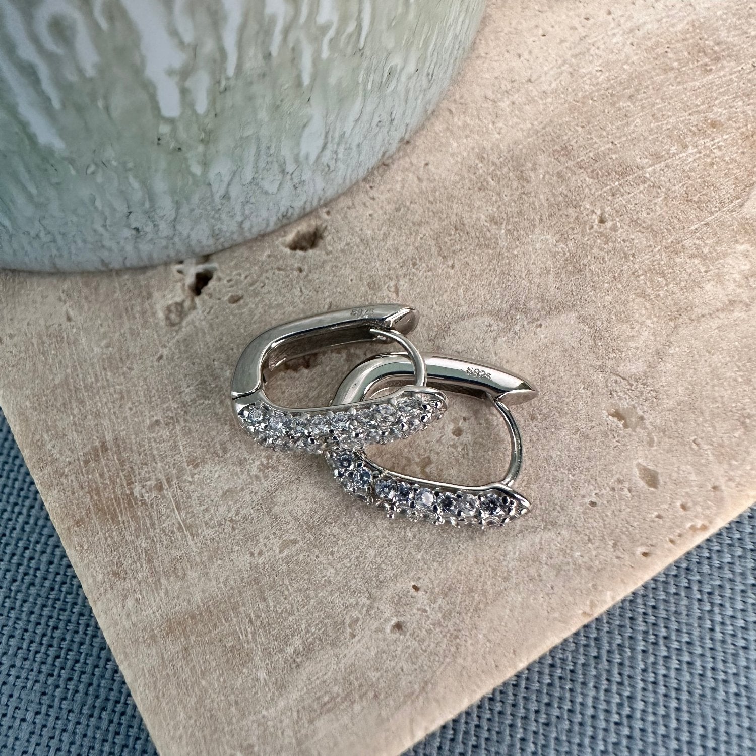 white gemstone pave silver hoop earing on a wooden board