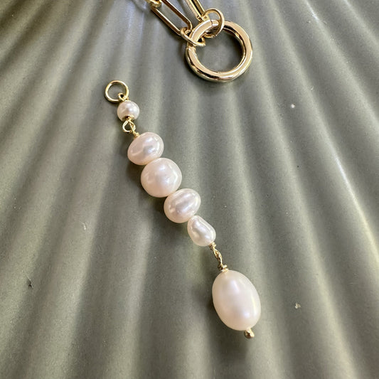 Gold Charm drop with natrual freshwater pearls on a textured grey ground