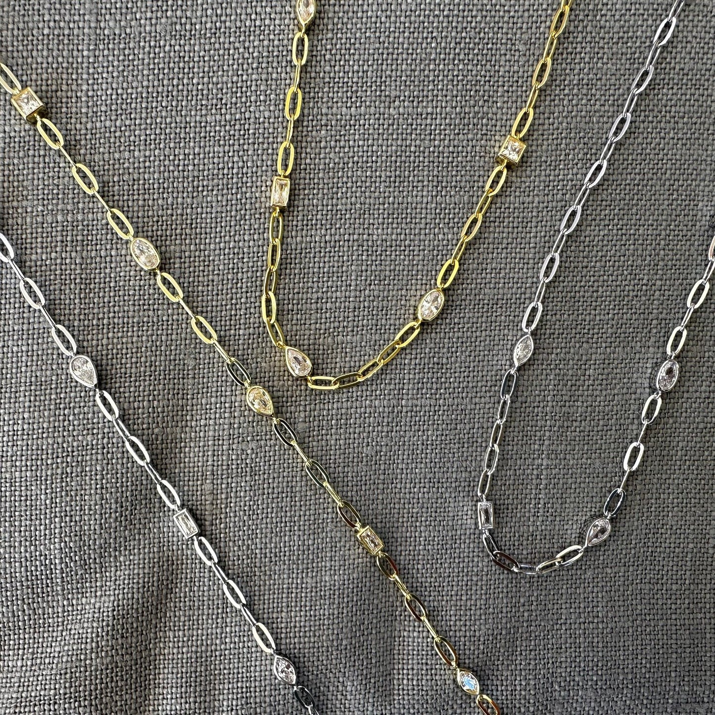 Bracelet and Necklace shown in both Silver and Gold on grey background