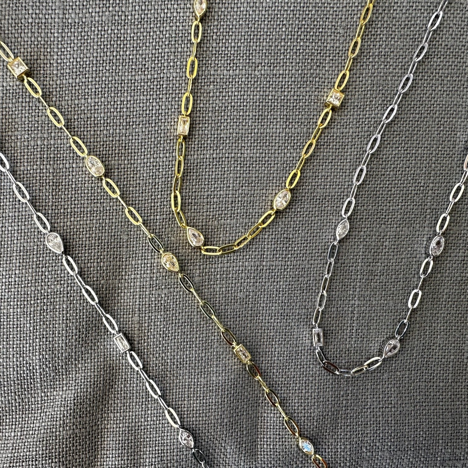 Bracelet and Necklace shown in both Silver and Gold on grey background