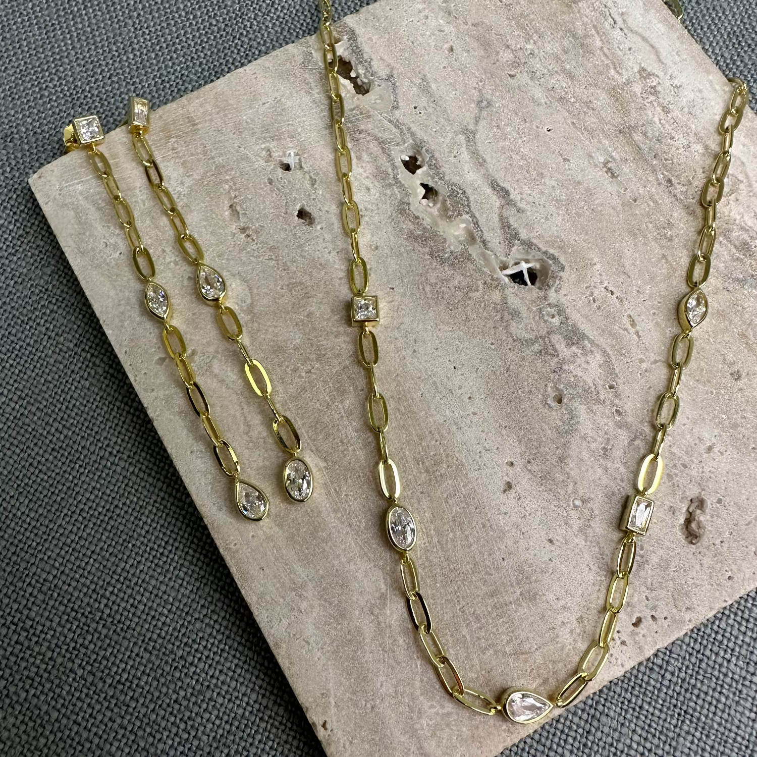 Necklace and earrings on terazzo tile, grey background