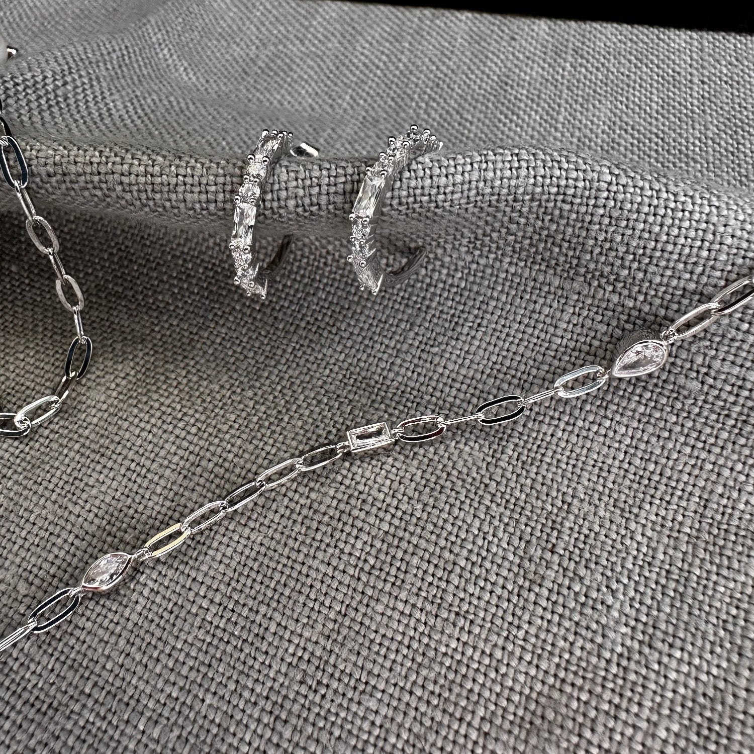 Silver hoop CZ earrings with gemstone necklace on grey background