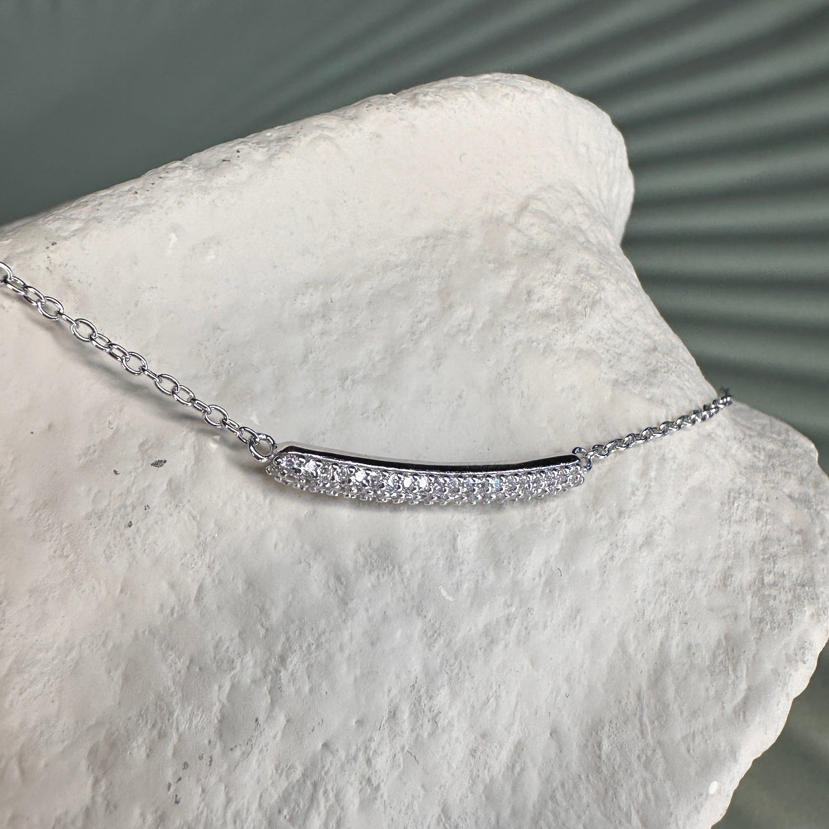 Silver bracelet with clear stones on a white stone surface