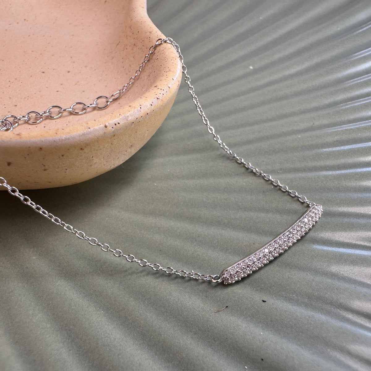 gemstone bracelet laid on ceramic dish on textured green ground