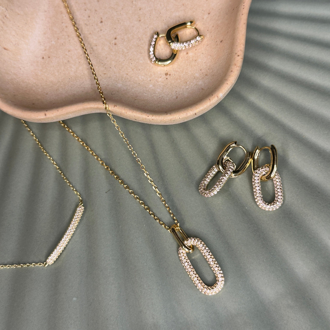 Gold necklace and earrings on a textured surface
