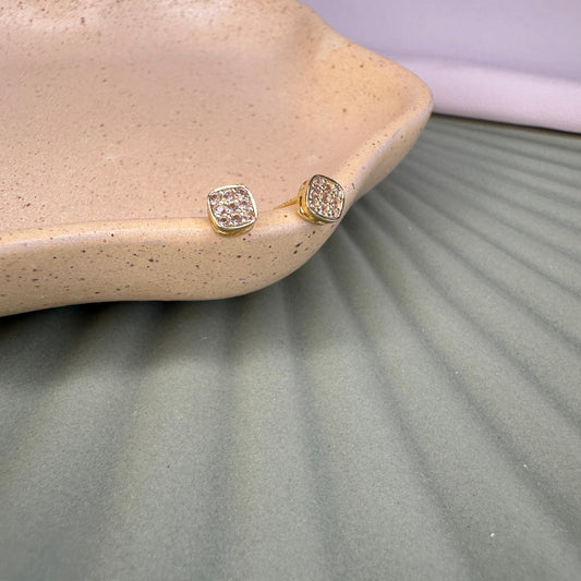 Gold earrings with  stones on a textured surfacelush colour