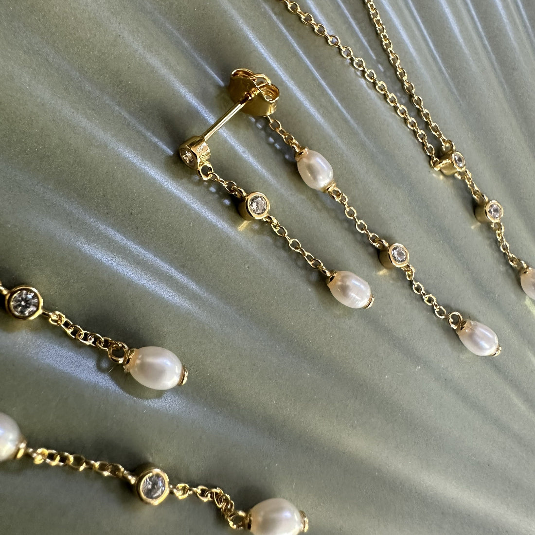 Gold necklace with real freshwater pearls and gemstone accents on a textured surface