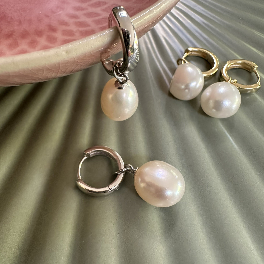 Pair of large freshwater pearl hoop earrings on a textured surface