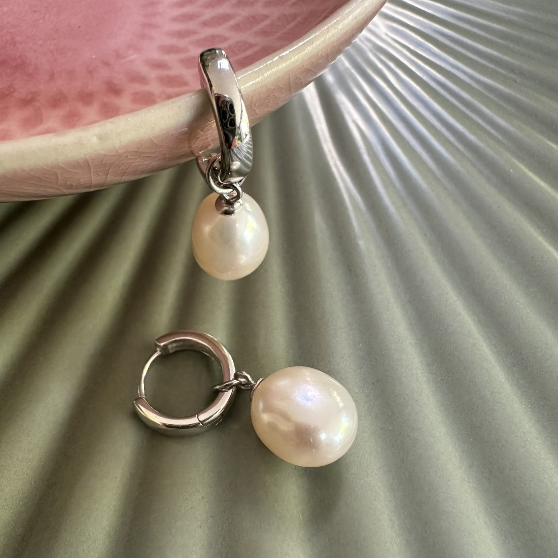 Large natural freshwater pearl huggies silver earrings on a textured surface