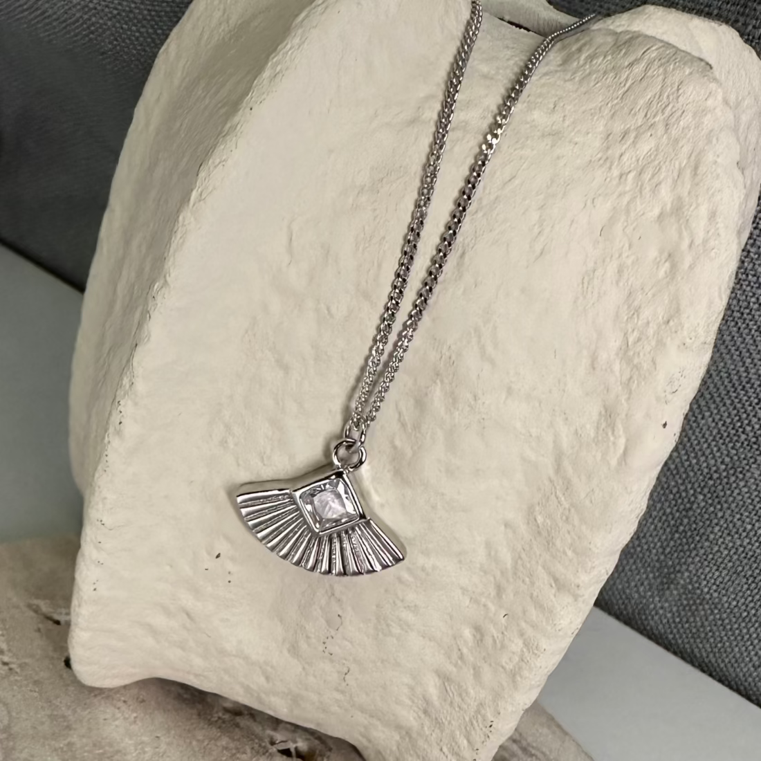 art deco inspired fan geometric design silver pendant laid on ceramic vase