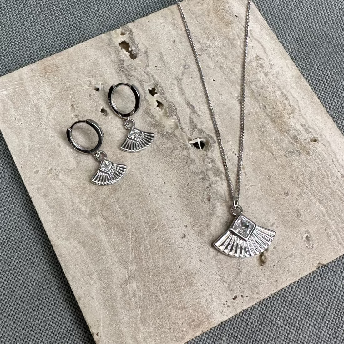 art deco inspired shaped fan with gemstone in a silver necklace and matching silver huggie earrings