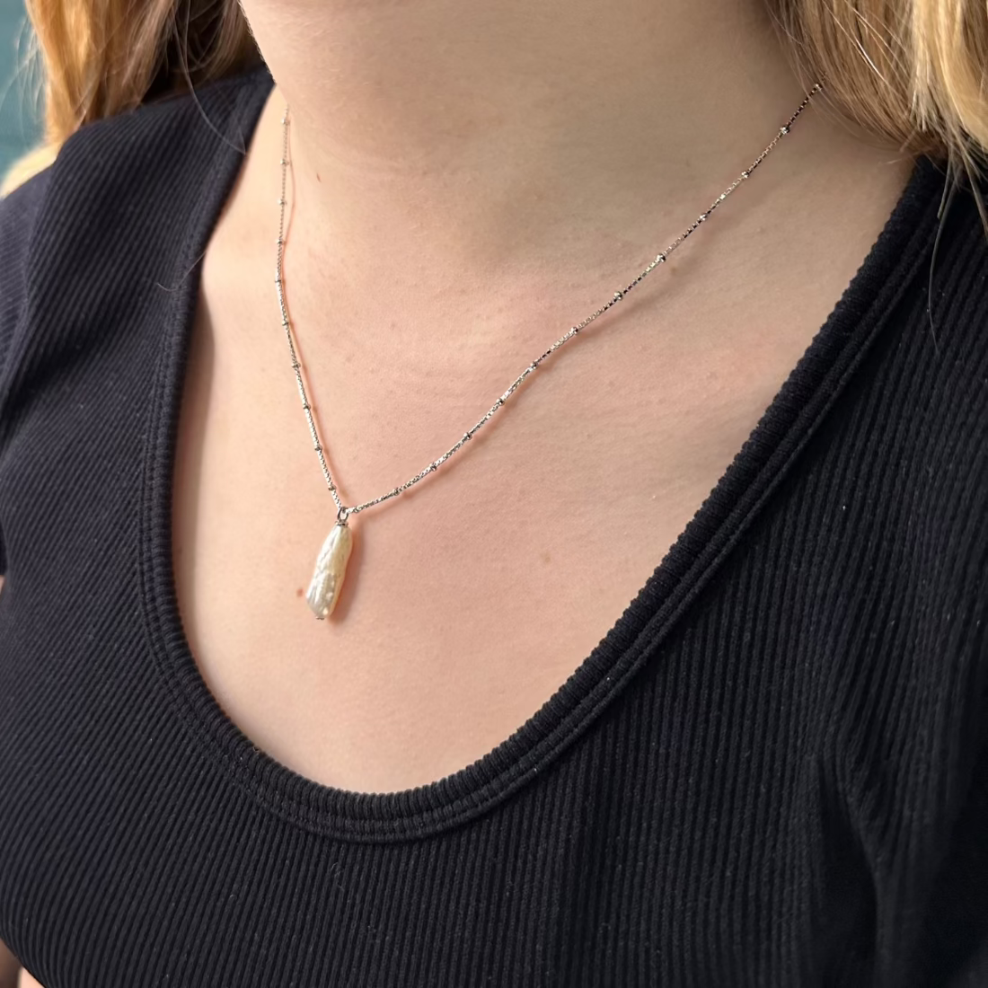 close up of mdels neck with baroque freshwatter pendant on ball chain in silver.