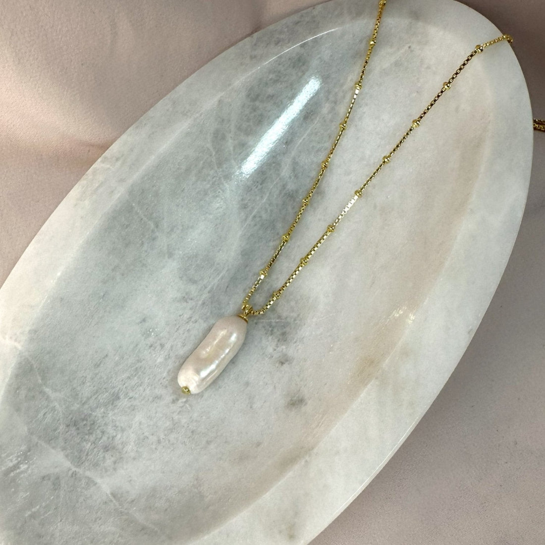 natural freshwater pearl baroque pendant necklace in gold on a ball chain for a modern gift laid on a marble tray