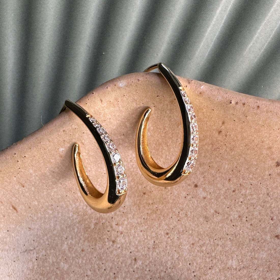Gold hoop earrings with gemstone detail on ceramic plate
