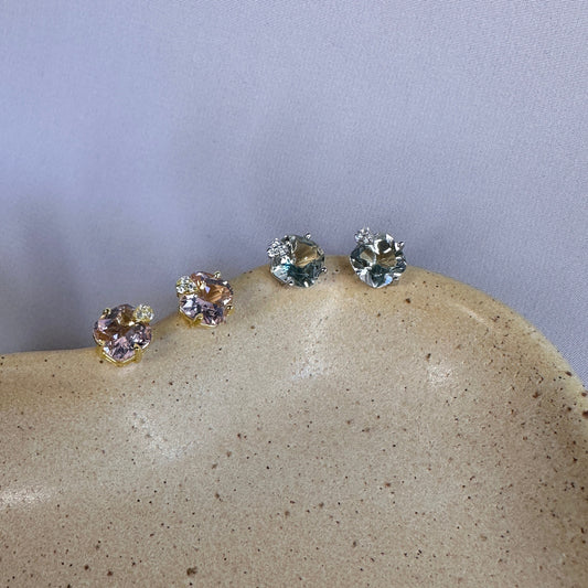 Set of four sterling silver stud earrings set with amethyst gemstones on a textured stone surface with a light gray background