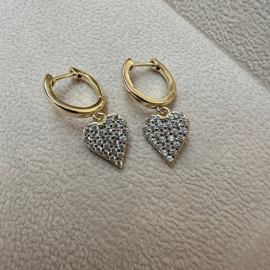 Gold hoop earrings with heart-shaped diamond pendants on a light gray surface