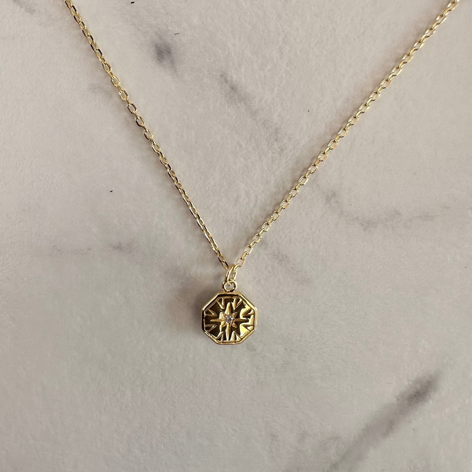gold hexagon necklace on grey ground