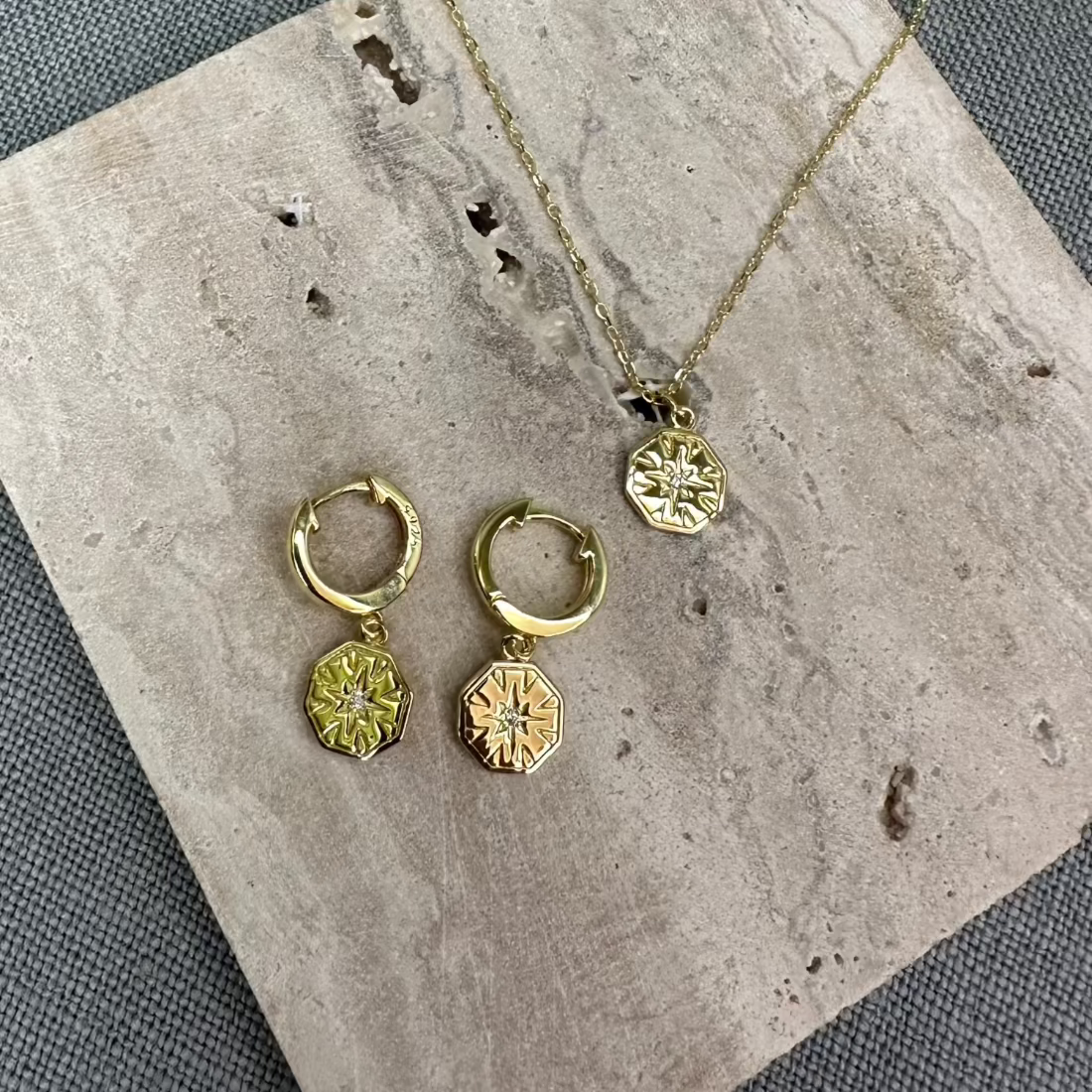 a collection of gold hexagon charm inspired jewellery laid on a marble tile