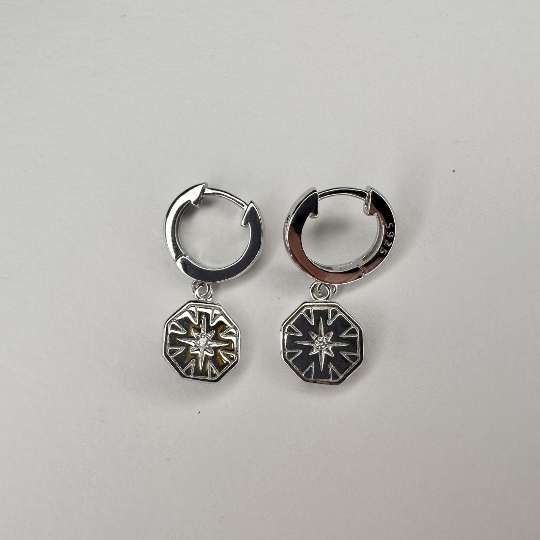 silver huggies with hexagon shaped charms with engraving and gemstone sparkle. on a white background