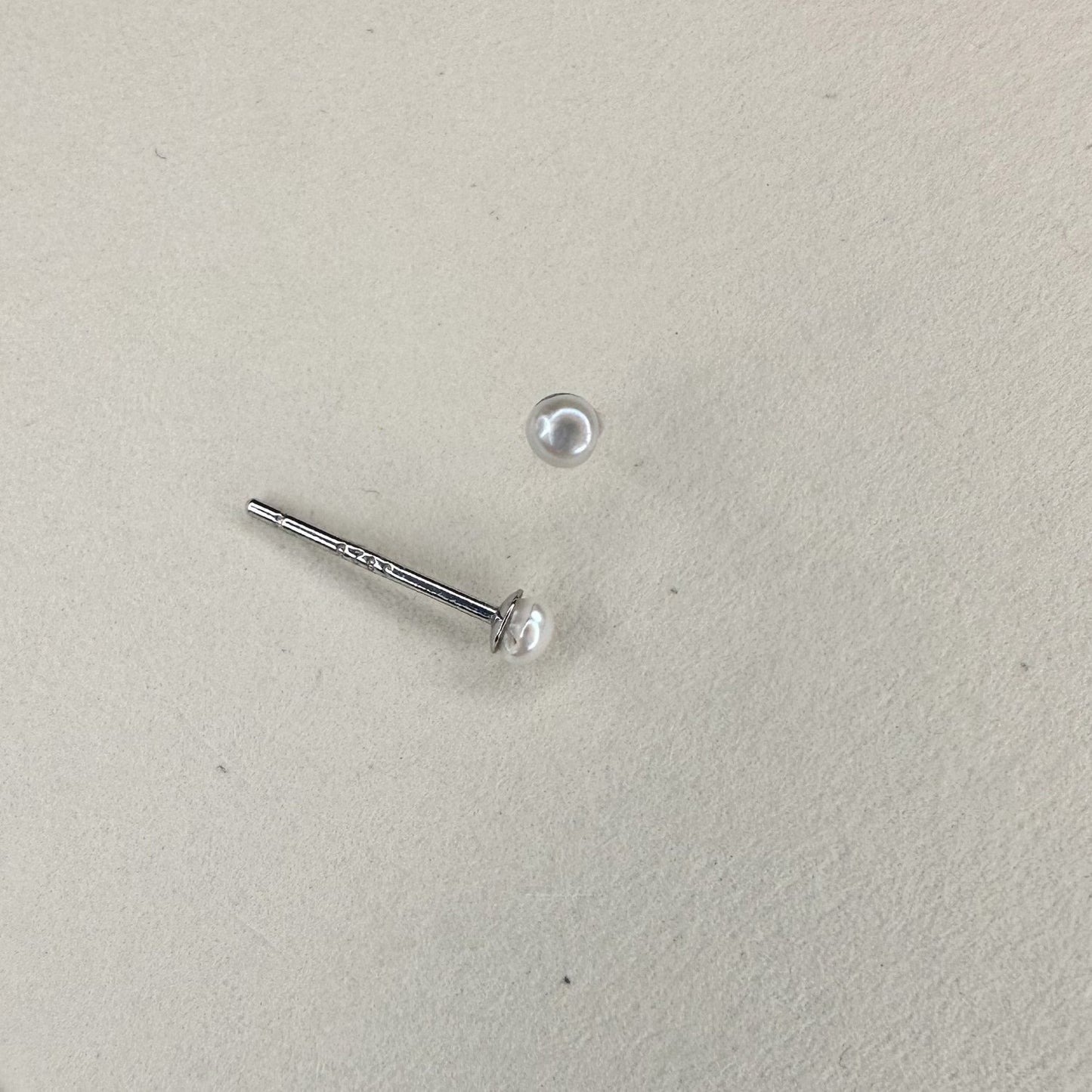 silver mini pearl studs on a white matte surface