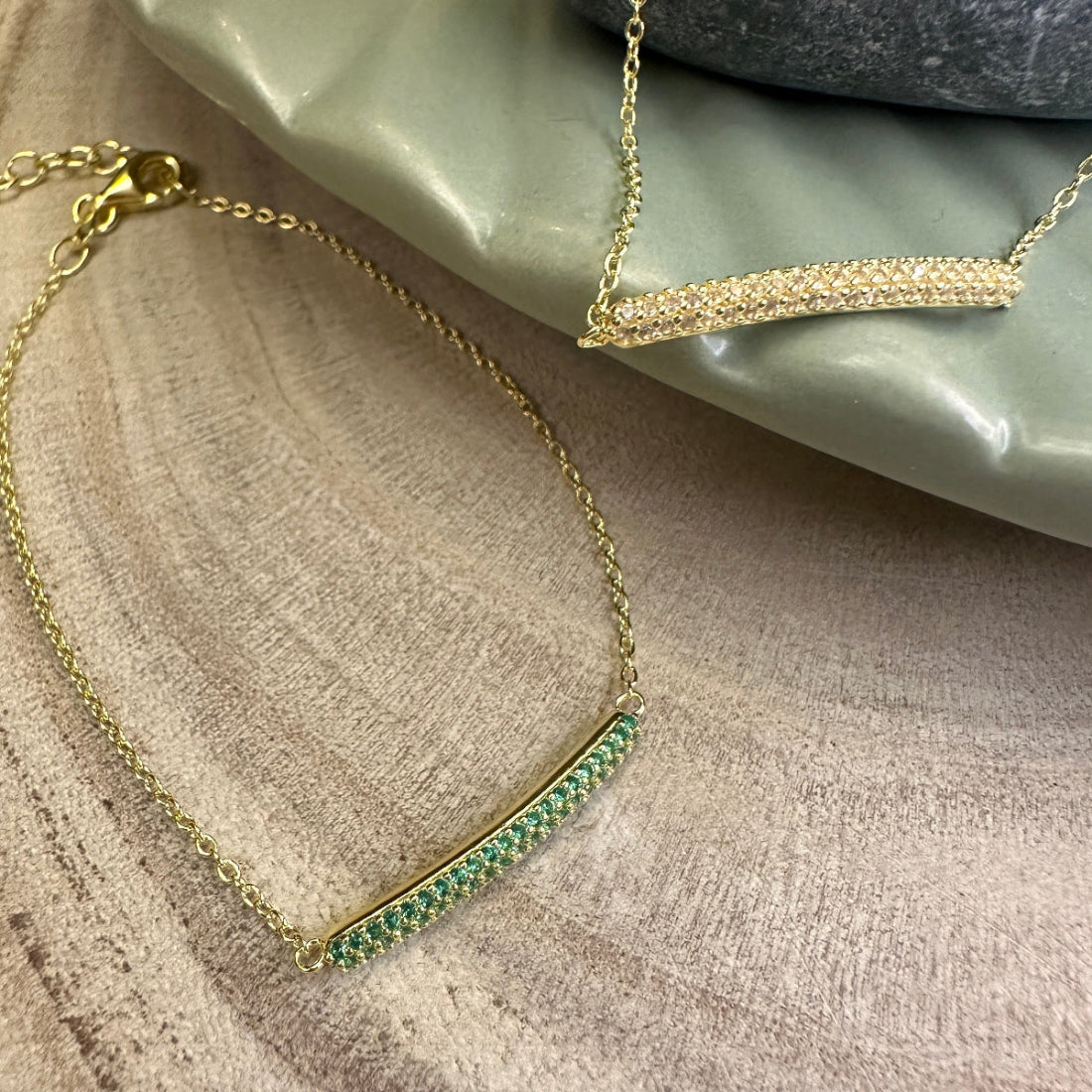 Gold bracelet with green gemstones on a textured surface