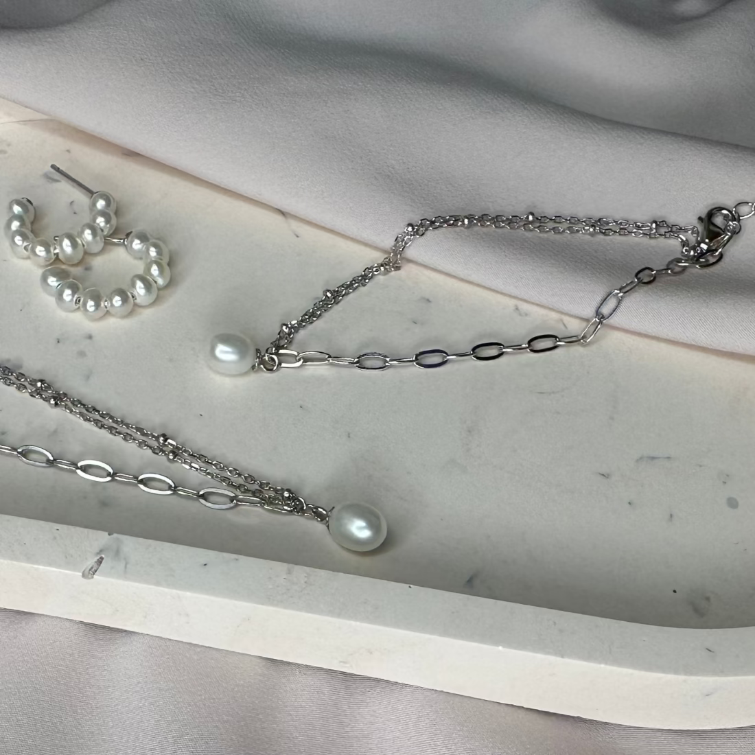 a collection of freshwater pearl silver jewellery laid on marble tray