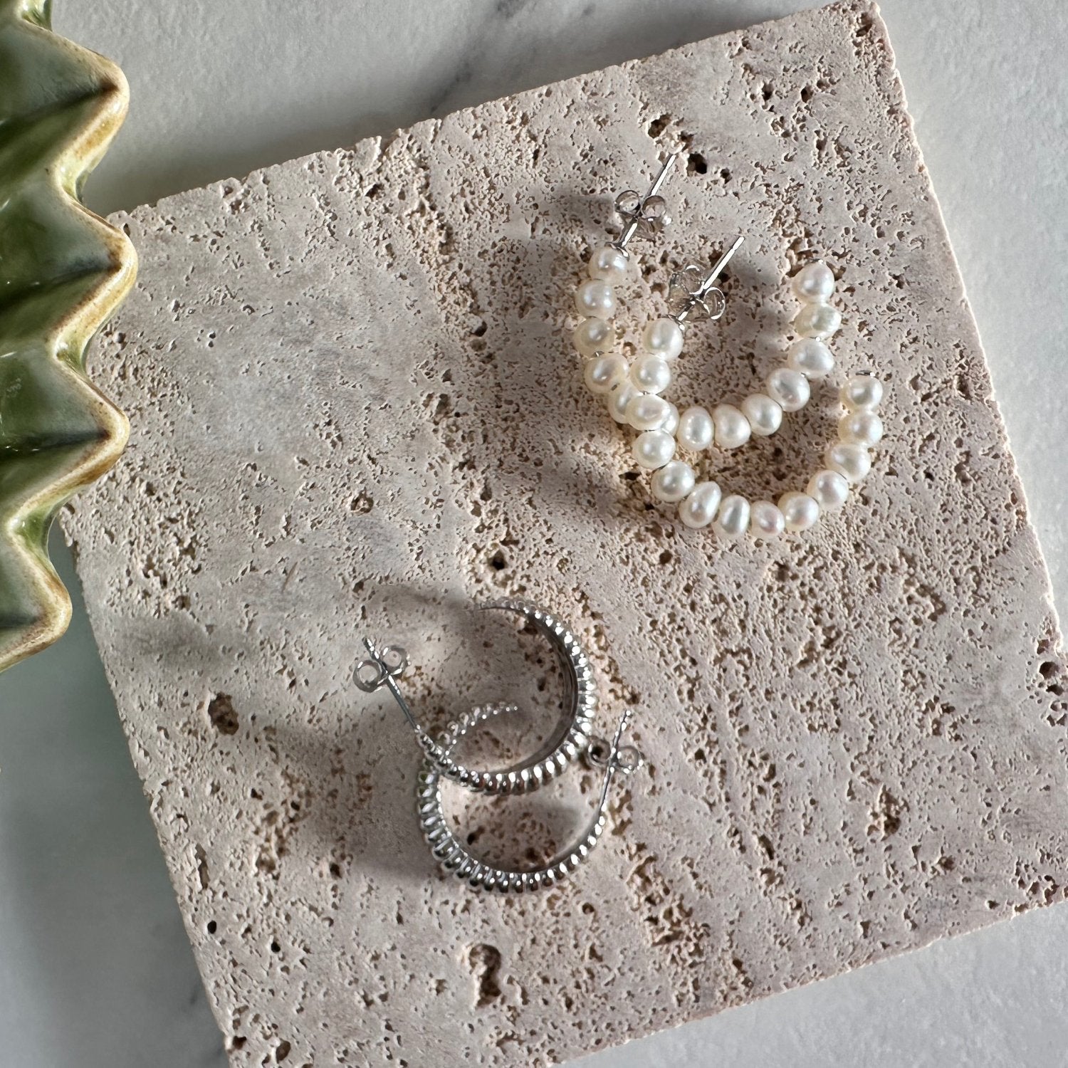 a collection of earings laid out on a wooden tile