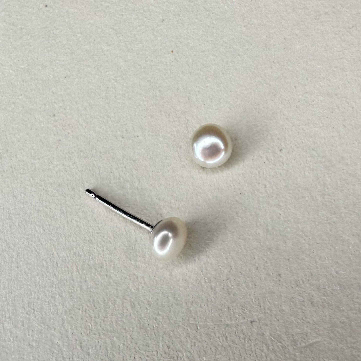 medium pearl silver stud earings on a white matte plate