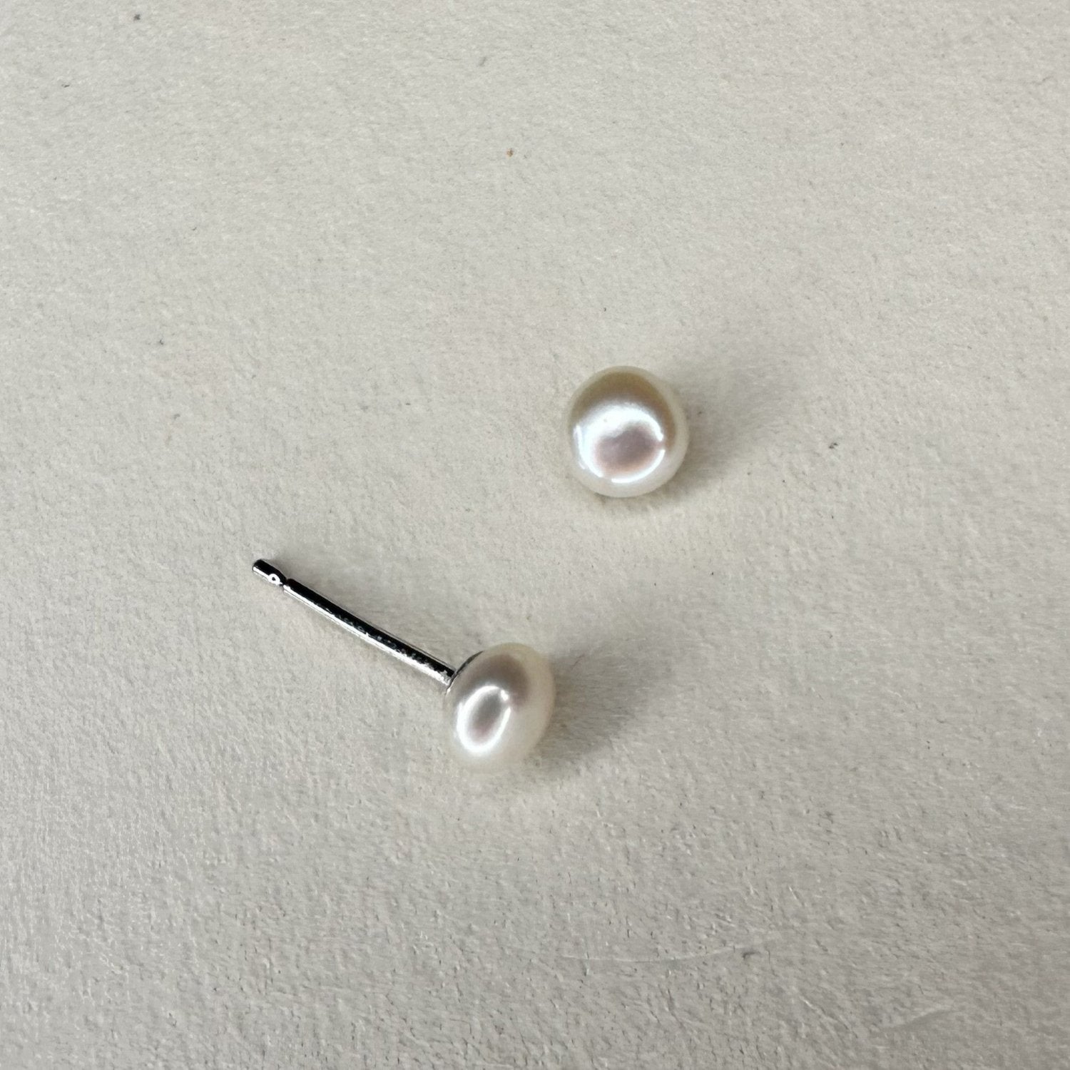 medium pearl silver stud earings on a white matte plate