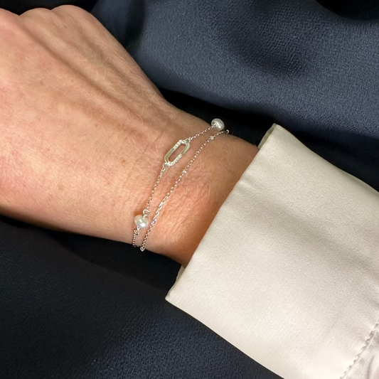 a close up image of model hand wearing a modern bracelet with oval gemstone charm.